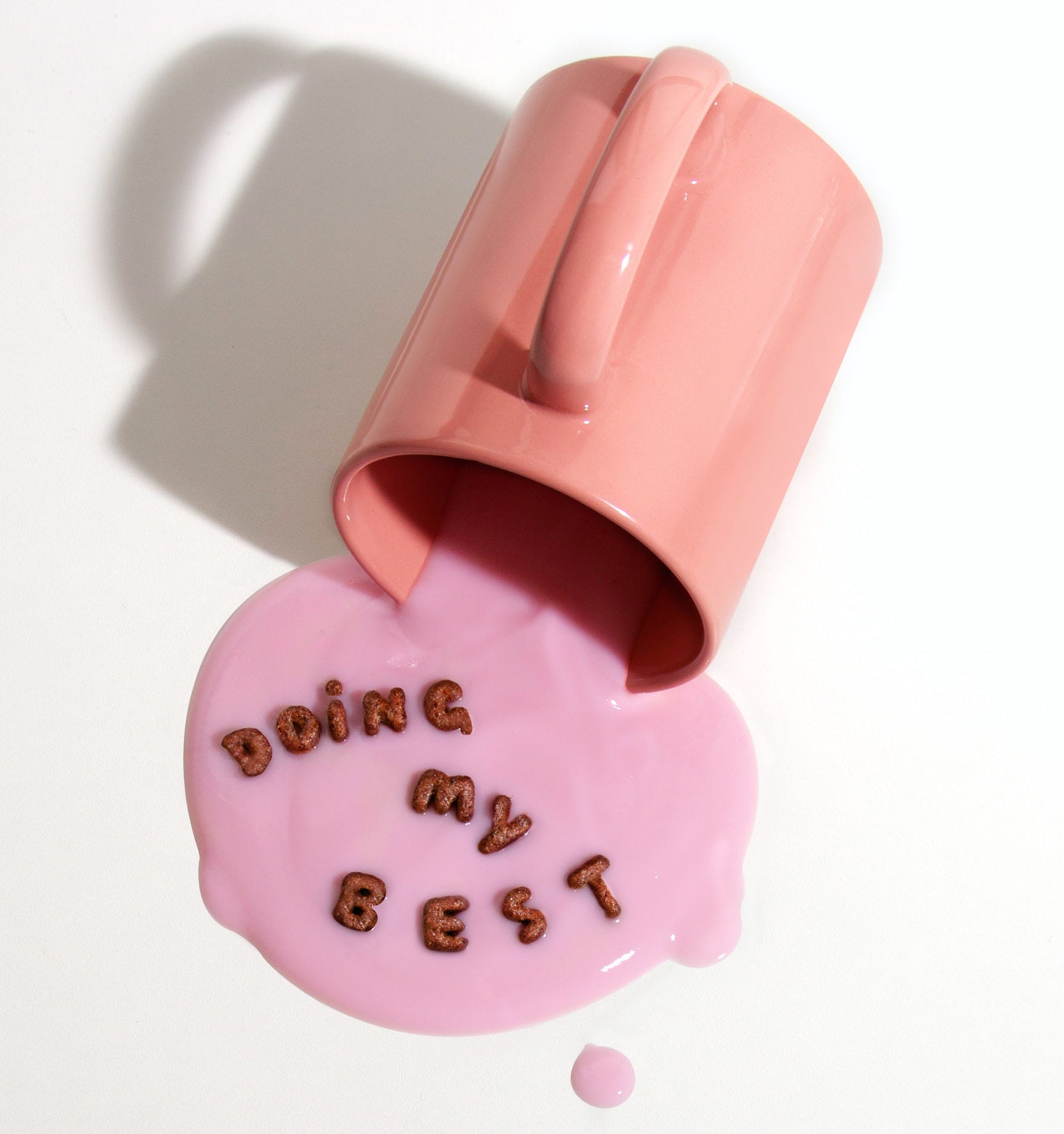 Peach mug with spilled pink yogurt and words “Doing my best” spelled out in cereal.